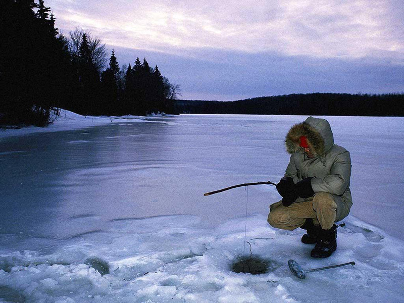 Person kneeling ice fishing